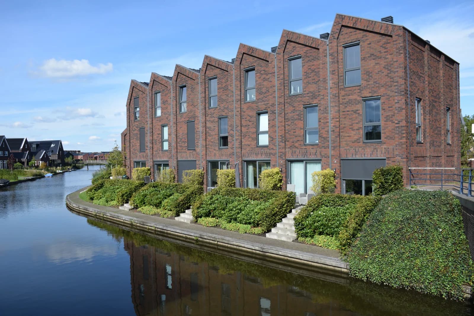 Moderne rijwoningen aan het water onder een blauwe lucht